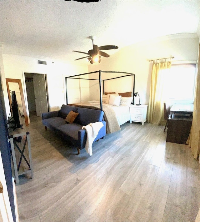 bedroom with a textured ceiling, wood-type flooring, and ceiling fan