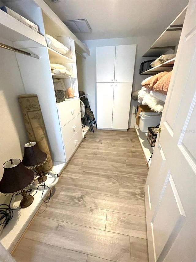 walk in closet with light hardwood / wood-style floors