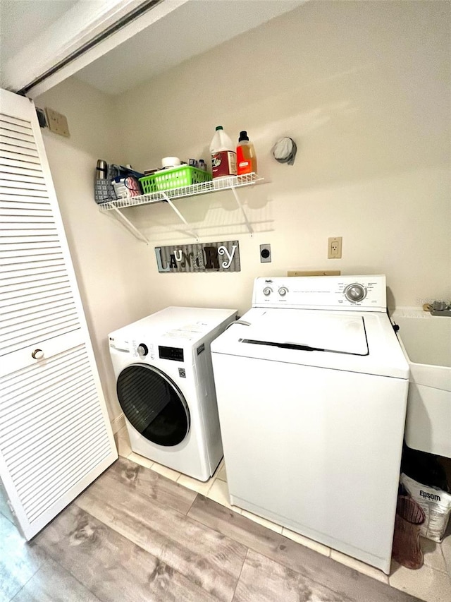 laundry area with washer and dryer, sink, and light wood-type flooring