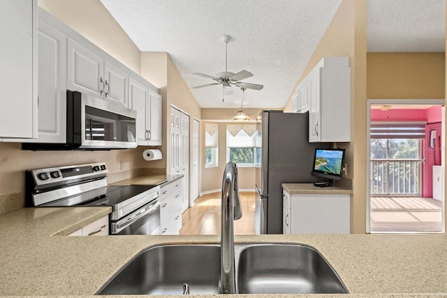 kitchen featuring a textured ceiling, stainless steel appliances, white cabinetry, and sink