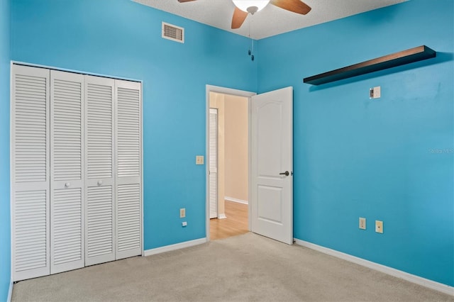 unfurnished bedroom with ceiling fan, light colored carpet, a textured ceiling, and a closet