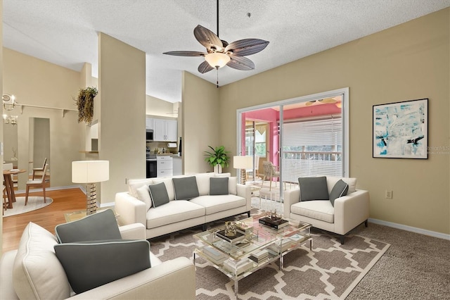 living room featuring ceiling fan with notable chandelier and a textured ceiling