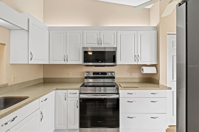 kitchen featuring white cabinets, stainless steel appliances, light stone counters, and sink