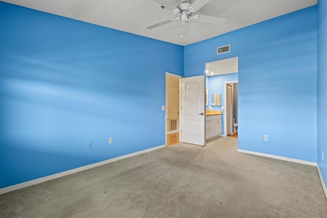 unfurnished bedroom featuring a textured ceiling, ceiling fan, ensuite bathroom, and light carpet