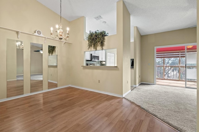 interior space featuring ceiling fan with notable chandelier, a textured ceiling, hardwood / wood-style flooring, and high vaulted ceiling