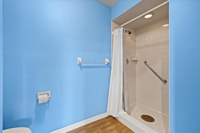 bathroom with toilet, wood-type flooring, and a shower with shower curtain