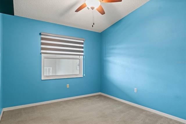 empty room with ceiling fan, light colored carpet, and a textured ceiling