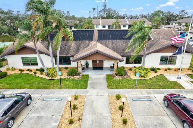 view of front of property with solar panels and a front lawn