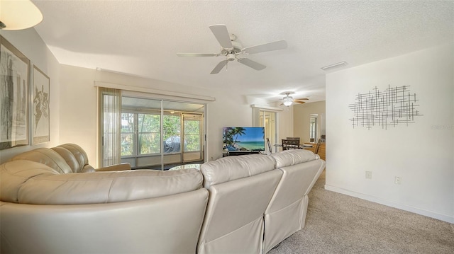 living room with a textured ceiling, light carpet, and ceiling fan