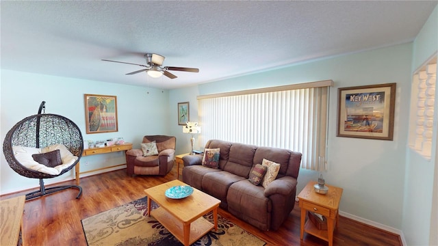 living room featuring ceiling fan, wood-type flooring, and a textured ceiling