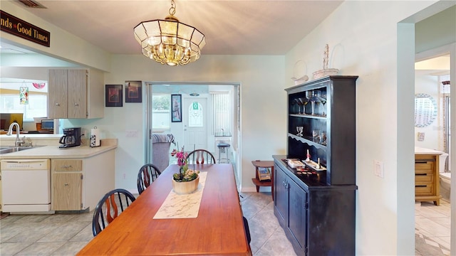 dining area with a chandelier, light tile patterned flooring, and sink