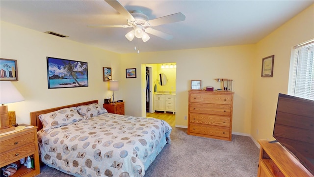 bedroom with light carpet, ensuite bath, and ceiling fan