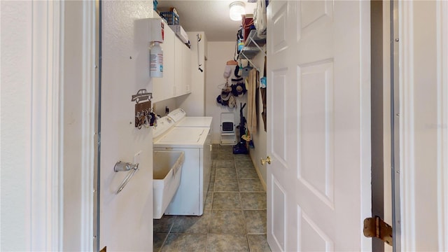 laundry room with washer and dryer, dark tile patterned flooring, and cabinets