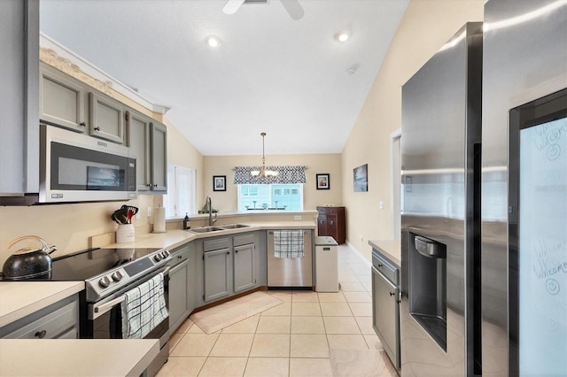 kitchen with pendant lighting, stainless steel appliances, lofted ceiling, and sink