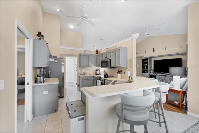 kitchen with stainless steel appliances, kitchen peninsula, sink, a breakfast bar area, and gray cabinets