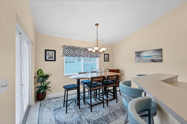 dining room with a notable chandelier, light tile patterned floors, and lofted ceiling