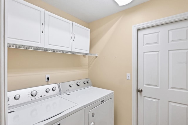 laundry area featuring washing machine and clothes dryer and cabinets