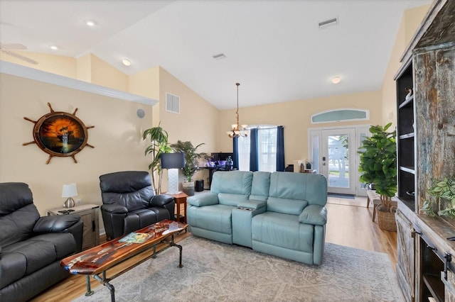 living area featuring an inviting chandelier, visible vents, vaulted ceiling, and light wood-style floors