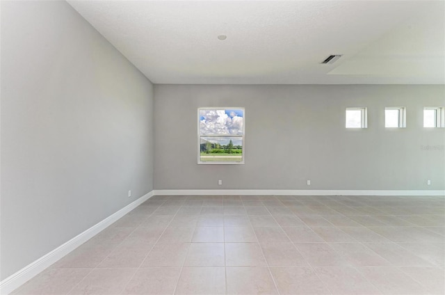 empty room featuring a textured ceiling and light tile patterned floors