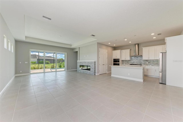 unfurnished living room featuring light tile patterned floors and a raised ceiling