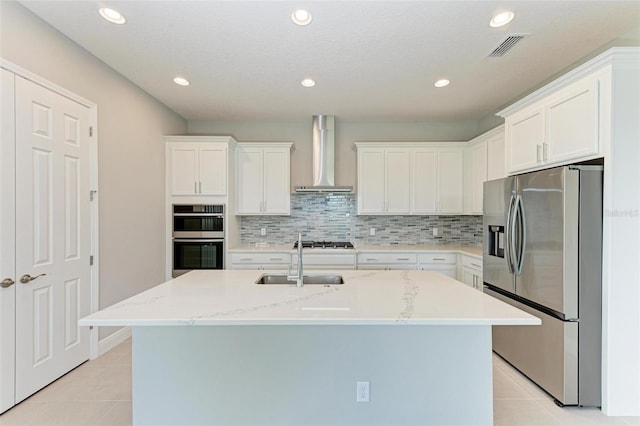 kitchen with wall chimney range hood, white cabinetry, sink, and appliances with stainless steel finishes