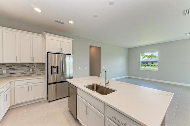 kitchen featuring a center island with sink, appliances with stainless steel finishes, decorative backsplash, sink, and white cabinets