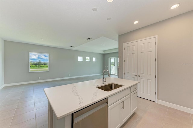 kitchen featuring light tile patterned flooring, sink, an island with sink, white cabinets, and dishwasher