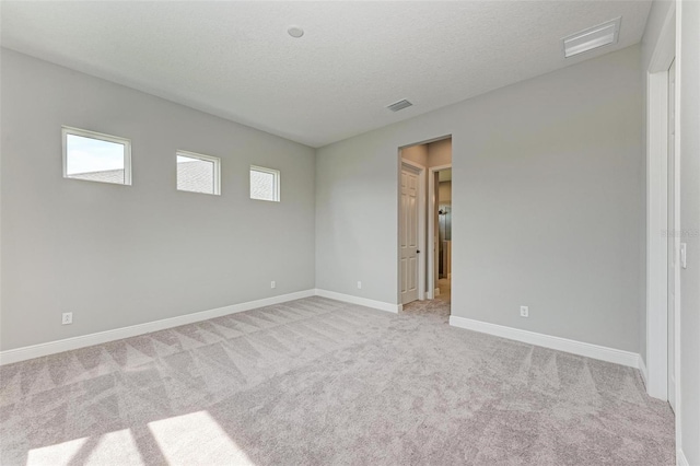 carpeted empty room featuring a healthy amount of sunlight and a textured ceiling