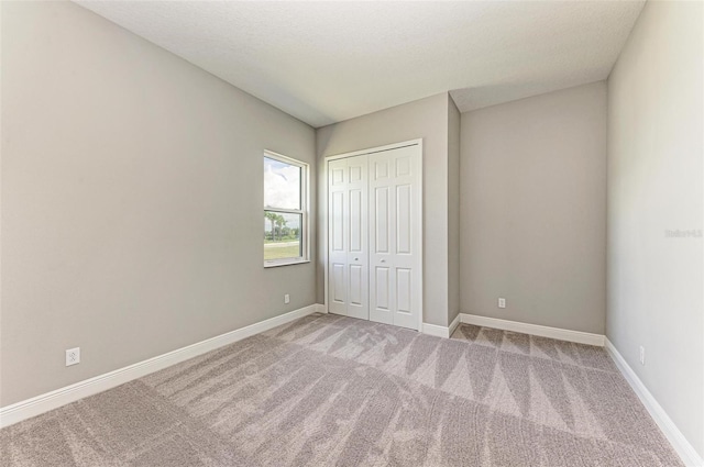 unfurnished bedroom featuring a textured ceiling, carpet flooring, and a closet