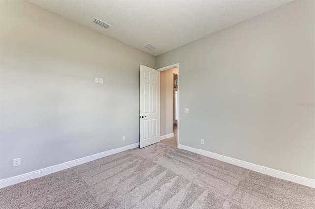 spare room featuring a textured ceiling and light carpet