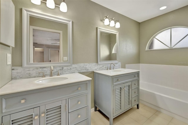 bathroom with a bathing tub, decorative backsplash, tile patterned flooring, and vanity