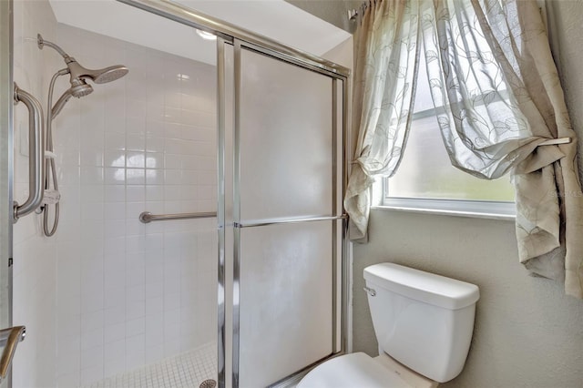 bathroom with a shower with door and toilet