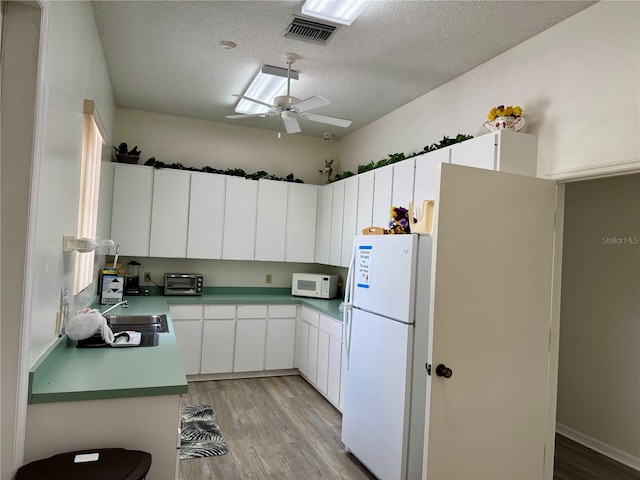 kitchen with light wood-type flooring, white appliances, a textured ceiling, sink, and white cabinets