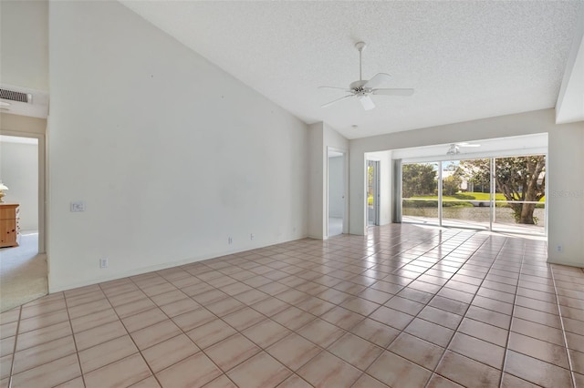 tiled empty room featuring a textured ceiling, vaulted ceiling, and ceiling fan