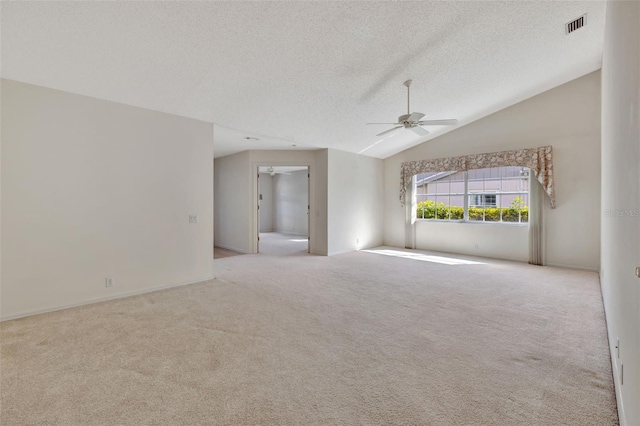 carpeted spare room featuring a textured ceiling, vaulted ceiling, and ceiling fan