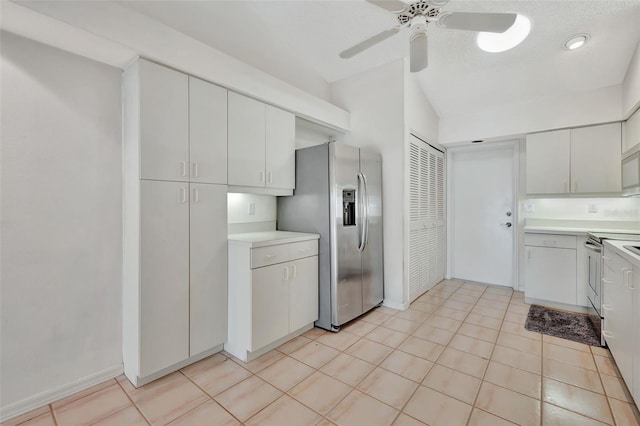 kitchen with lofted ceiling, white cabinets, ceiling fan, light tile patterned floors, and appliances with stainless steel finishes