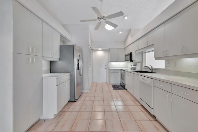 kitchen with vaulted ceiling, ceiling fan, a textured ceiling, appliances with stainless steel finishes, and white cabinetry