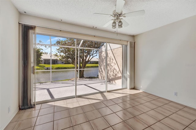 tiled spare room with a textured ceiling, a water view, and ceiling fan