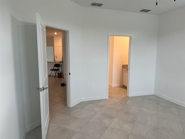 unfurnished bedroom featuring light tile patterned floors and ensuite bath