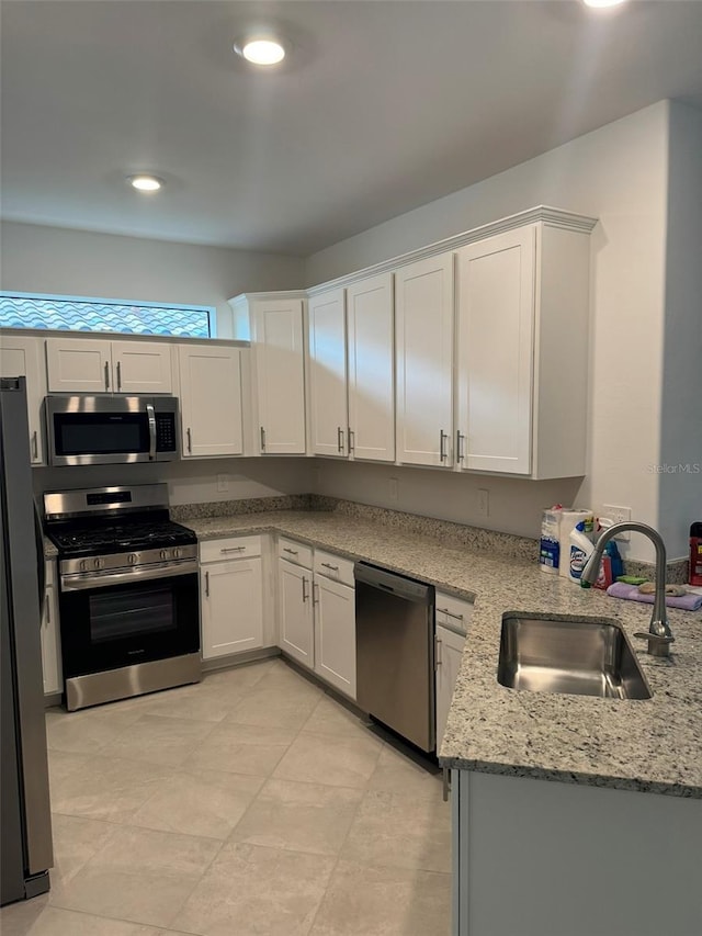 kitchen featuring light stone countertops, sink, stainless steel appliances, kitchen peninsula, and white cabinets