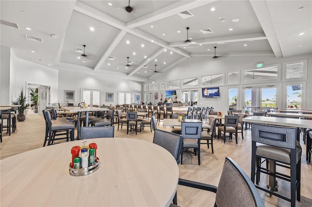 dining space featuring ceiling fan, high vaulted ceiling, and light hardwood / wood-style flooring