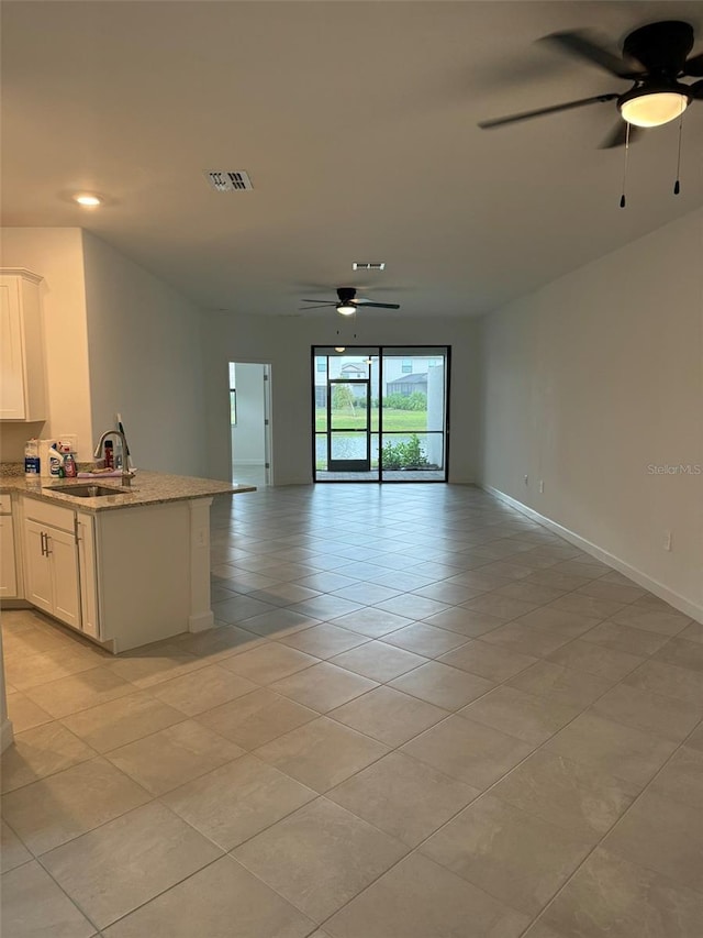 unfurnished living room featuring light tile patterned floors, ceiling fan, and sink