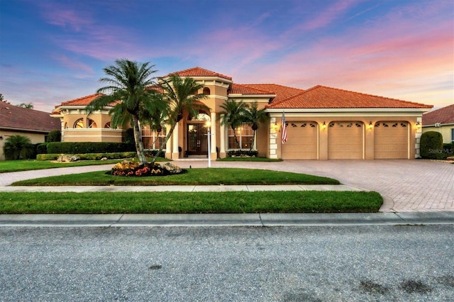 mediterranean / spanish-style house featuring stucco siding, a garage, driveway, and a tiled roof