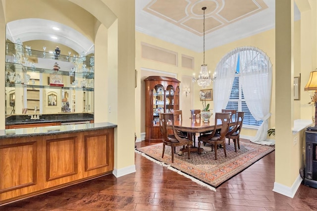 dining space with dark wood-type flooring, a chandelier, sink, and crown molding