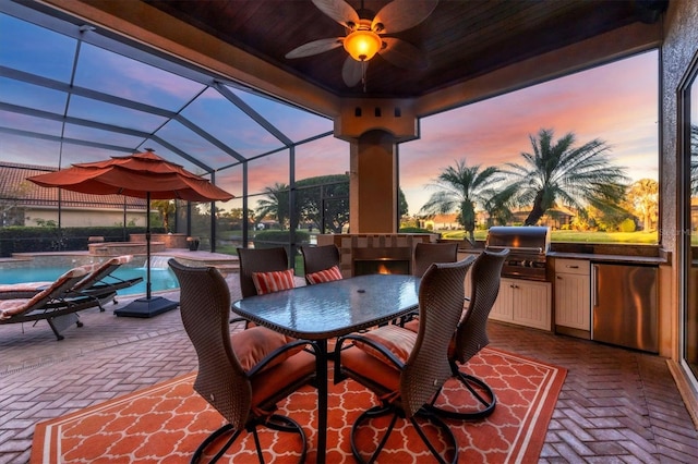 patio terrace at dusk with ceiling fan, a lanai, and area for grilling