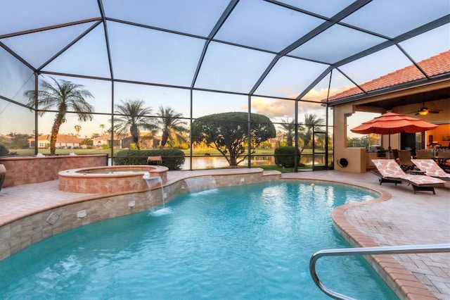 pool at dusk featuring a patio, a lanai, pool water feature, and an in ground hot tub