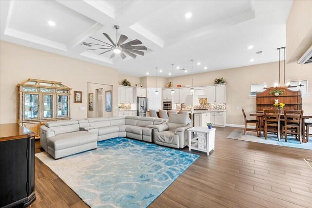 living room with ceiling fan, light wood-type flooring, crown molding, and coffered ceiling