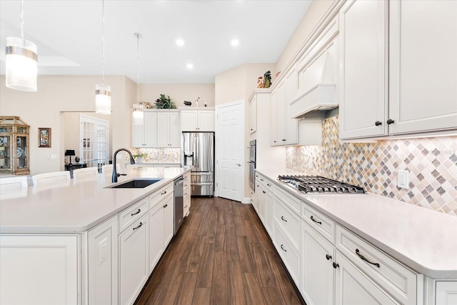 kitchen with stainless steel appliances, decorative light fixtures, dark hardwood / wood-style floors, sink, and a spacious island