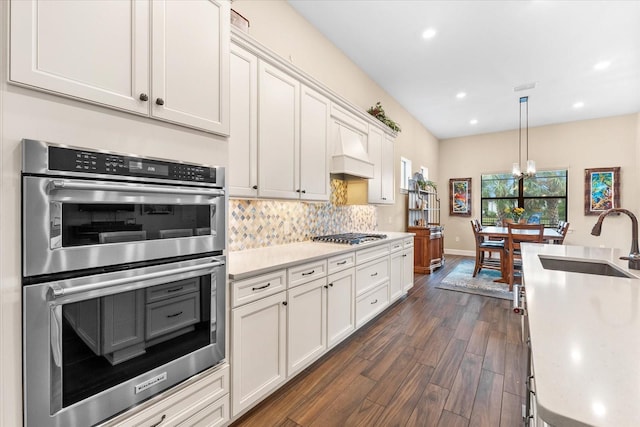 kitchen featuring stainless steel appliances, white cabinetry, dark hardwood / wood-style flooring, pendant lighting, and sink