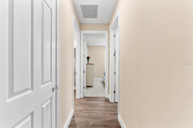 hallway featuring dark wood finished floors, baseboards, and visible vents